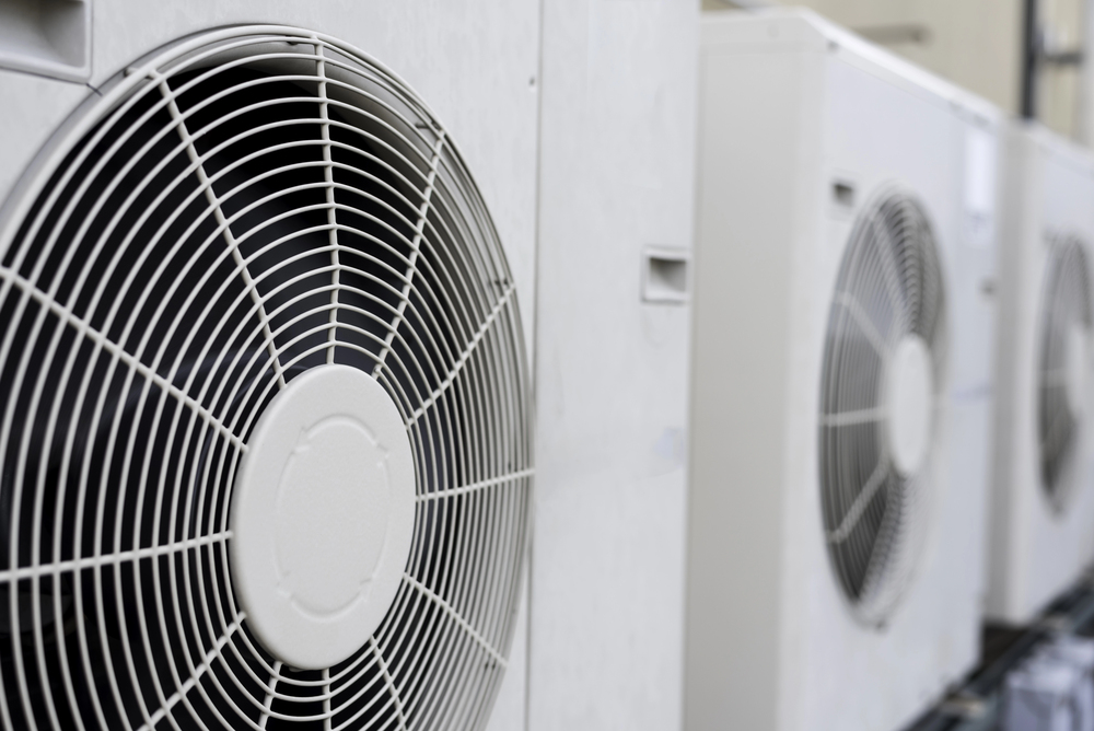 Close-up view of several white outdoor air conditioning units with prominent circular fans.